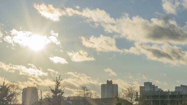 İlk kar şehirdeki yerleşim yerlerini kaplıyor. Güneş ışığı ve bulutlu gökyüzü. Şehir kavramları. Arka planda yüksek binalar var..