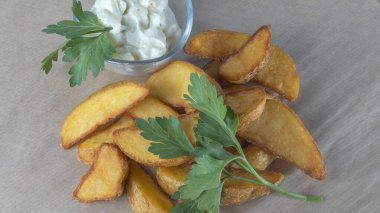 Soslu patates dilimleri ve parşömen üzerine izole edilmiş maydanoz manzarası. Fast food kavramları.