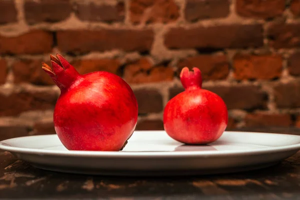 Due Succose Melograno Spagnolo Frutta Piatto Porcellana Uno Sfondo Muro — Foto Stock