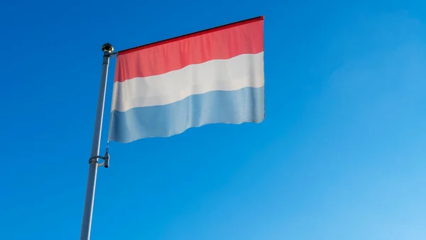 太陽光線とレンズフレアを持つ青い空の前の旗竿にルクセンブルクの国旗 外交概念 国際関係 テキストのスペース — ストック写真