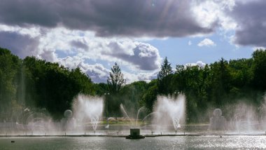 Çeşmeden su. Bulutlu gökyüzünün arkasındaki çeşme akıntısının tepesinde. Nehirdeki çeşme dramatik gökyüzüne karşı.
