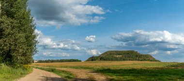 Kapalı şehir çöplüğü. Bölgenin restorasyonu. Büyük bir çöp yığınının peyzajı. Arka planda bir metropol ve bulutlu mavi bir gökyüzü var. Ekolojik sorun.