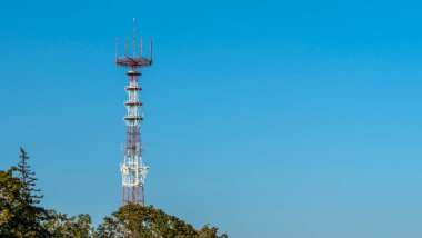 Mavi gökyüzü arka planında cep telefonu antenleri olan televizyon ve radyo kulesi..