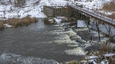 Bir yaya köprüsünün altındaki kış nehrinde kaynar su. Soyut arkaplan. Mesaj için yer var. Doğa kavramları.