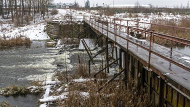 Kış nehri üzerindeki dar eski ahşap köprü. Kırsal kesimdeki nehir üzerinde tahta yaya köprüsü. Kış manzarası. Doğa kavramları.