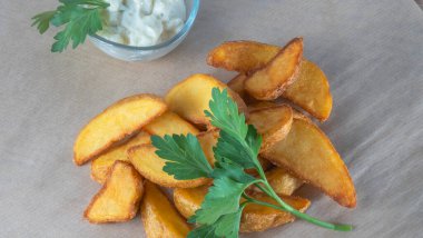 Soslu patates dilimleri ve parşömen üzerinde maydanoz. Fast food kavramları.