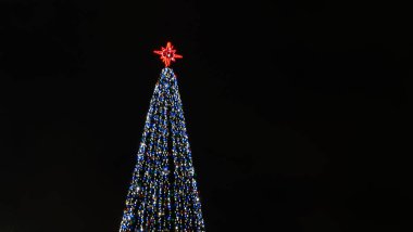 Noel ağacının ışıkları Bokeh 'i karanlık arka planda fotokopi aletiyle bulanıklaştırdı. Soyut şenlik arka planı. Metin için boşluk.