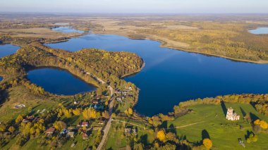 Sonbahar ormanı ve göl. Yukarıdan bak. Güneşli Sonbahar Gününde Göldeki Bir Adanın Hava Fotoğrafı. Doğa konsepti.