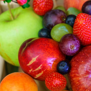 Yaz meyveleri, böğürtlen çeşitleri. Büyük elma, erik, kayısı, üzüm ve çilek. Masadaki ahşap sandıkta renkli meyveler..