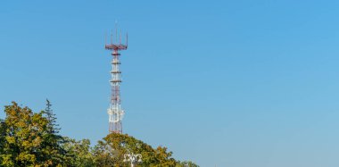 Mavi gökyüzü arka planında cep telefonu antenleri olan televizyon ve radyo kulesi..