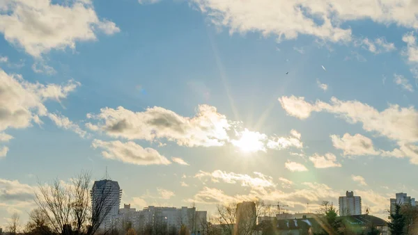 İlk kar şehirdeki yerleşim yerlerini kaplıyor. Güneş ışığı ve bulutlu gökyüzü. Şehir kavramları. Arka planda yüksek binalar var..