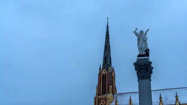 天使長マイケルの伝統的な彫刻は 劇的な空と教会の尖塔に対して槍で悪魔を打つ テキスト用のスペース 宗教の概念 — ストック写真