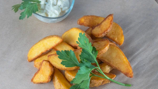 Soslu patates dilimleri ve parşömen üzerinde maydanoz. Fast food kavramları.