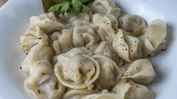 Kaynamış etli börek. Rus kaynamış pelmeni 'nin beyaz tabakta yakın plan görüntüsü. Haşlanmış ev yapımı Rus köftesi ya da etli pelmeni..