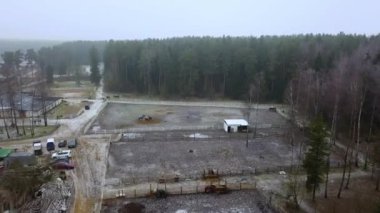 Atlar kışın bir çiftlikte ayrı avluda dururlar. Havadan geniş açı. Kırsal kavram.