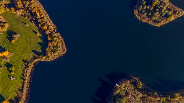 Sonbahar ormanı ve göl manzarası. Orman gölü üzerinde sonbahar güneşli bir akşam. Kırsal alan.