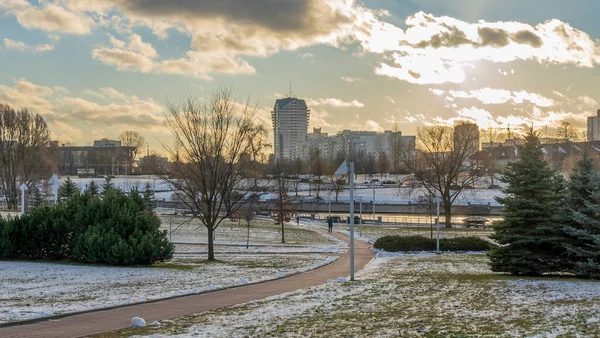 İlk kar şehirdeki yerleşim yerlerini kaplıyor. Güneş ışığı ve bulutlu gökyüzü. Şehir kavramları. Arka planda yüksek binalar var..