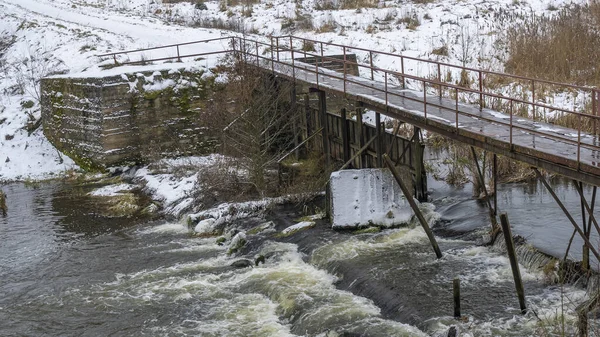 Bir yaya köprüsünün altındaki kış nehrinde kaynar su. Soyut arkaplan. Mesaj için yer var. Doğa kavramları.
