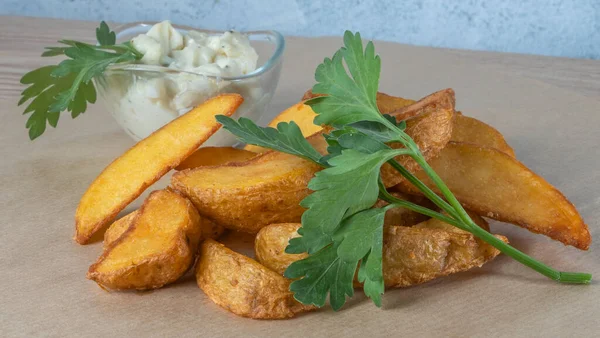 Soslu patates dilimleri ve parşömen üzerinde maydanoz. Fast food kavramları.