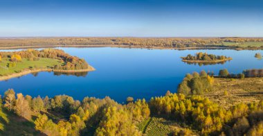 Sonbahar ormanı ve göl. Yukarıdan bak. Güneşli Sonbahar Gününde Göldeki Bir Adanın Hava Fotoğrafı. Doğa konsepti.