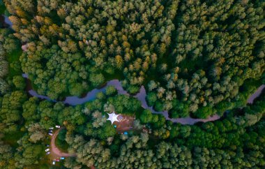 Tatillerde en iyi kamp manzarası. Nehir kıyısındaki ormanda turist çadırları. Hava görünümü.