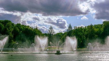 Çeşmeden su. Bulutlu gökyüzünün arkasındaki çeşme akıntısının tepesinde. Nehirdeki çeşme dramatik gökyüzüne karşı.