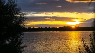 Göldeki şafak güneşinin ışınları. Nehirdeki günbatımı bulutlarının yansıması. Kırsal alan. Panoramik pankart. Doğa konsepti.