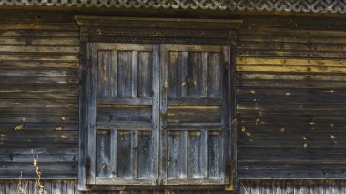 Rustic house wall with closed window and cracked paint. Space for text. Countryside concept.