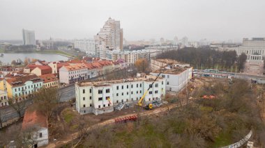 Minsk 'in merkezindeki eski hastane binasının hava manzaralı yıkımı ve yeniden inşası. Ekipmanların yardımıyla işçiler büyük bir şehirde eski bir binayı yıkıyorlar.
