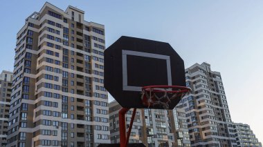 Modern yerleşim bölgesinde klasik mavi gökyüzü arka planında sedyesi olan basketbol potası. Sağlıklı bir yaşam tarzı. Sokak basketbolu oynamak için.