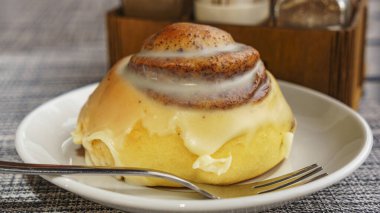 Close-up top view of cinnamon bun on plate and fork. Coffee and dessert concept. Space for text.