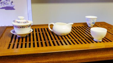 Small tea sets for sale with tea ceremony board on tourist market. Ceramic tea pot and cup with handmade ornament. Chinese tea ceremony set with traditional white and blue pattern. Cute tea set souvenir