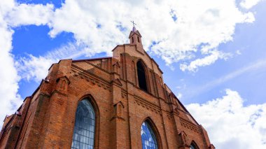 Neo-gothic red catholic church on classic blue sky background.