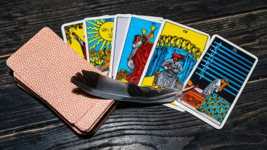 Tarot cards and bird feather on wooden background. Mystical and divination concept.