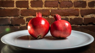 İki meyve sulu İspanyol nar porselen tabakta kırmızı tuğladan bir arka planda. Sağlıklı yaşam kavramları.