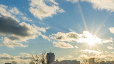 İlk kar şehirdeki yerleşim yerlerini kaplıyor. Güneş ışığı ve bulutlu gökyüzü. Şehir kavramları. Arka planda yüksek binalar var..