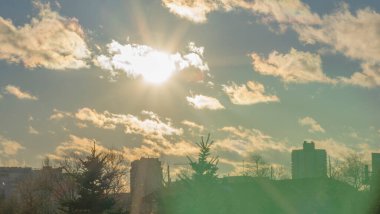 İlk kar şehirdeki yerleşim yerlerini kaplıyor. Güneş ışığı ve bulutlu gökyüzü. Şehir kavramları. Arka planda yüksek binalar var..