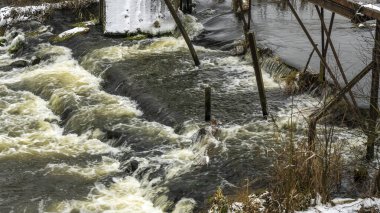 Bir yaya köprüsünün altındaki kış nehrinde kaynar su. Soyut arkaplan. Mesaj için yer var. Doğa kavramları.