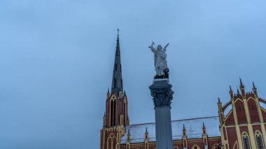 Geleneksel bir Başmelek Michael heykeli dramatik gökyüzüne ve kilise kulesine karşı şeytana mızrakla vuruyor. Mesaj için yer var. Din kavramları.