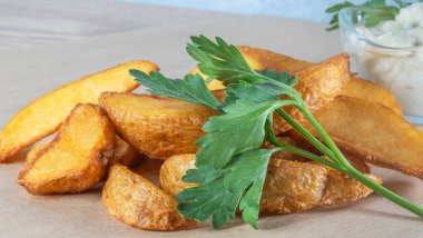Soslu patates dilimleri ve parşömen üzerinde maydanoz. Fast food kavramları.