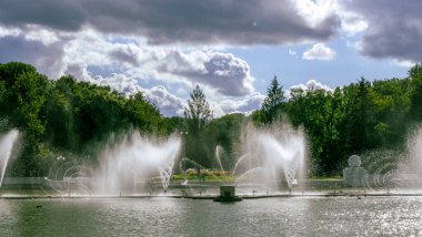 Çeşmeden su. Bulutlu gökyüzünün arkasındaki çeşme akıntısının tepesinde. Nehirdeki çeşme dramatik gökyüzüne karşı. Şehir manzarası görünümü.