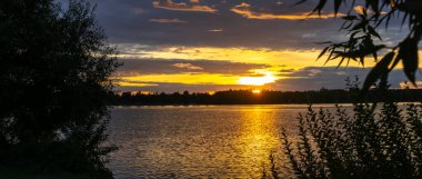 Göldeki şafak güneşinin ışınları. Nehirdeki günbatımı bulutlarının yansıması. Kırsal alan. Panoramik pankart. Panoramik pankart. Doğa konsepti.