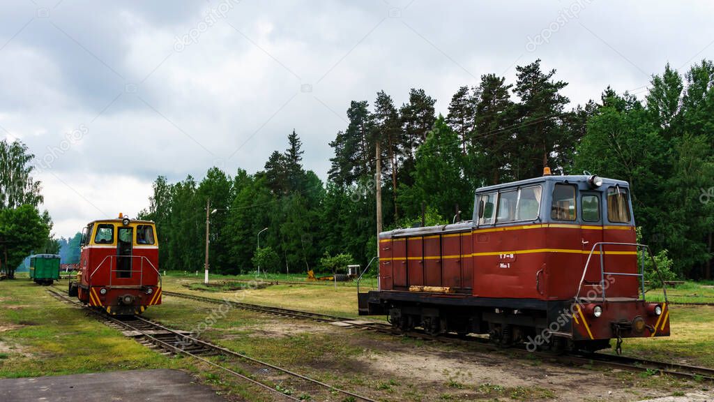 Photo of two narrow gauge railway locomotives on forest background. Extraction and transportations of peat. Space for text.