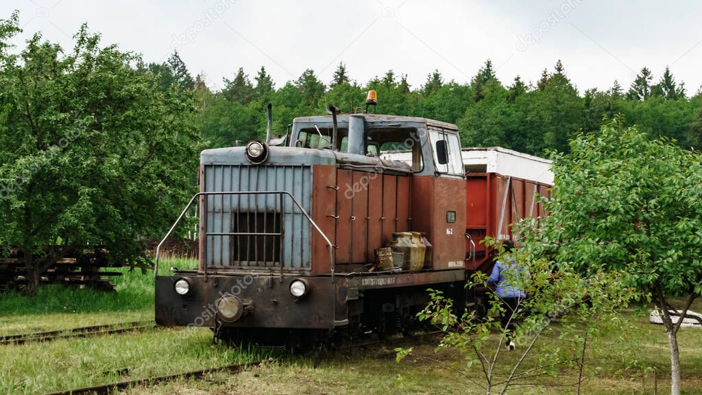 View of a narrow gauge railway locomotive on forest background. Extraction and transportations of peat. Space for text.