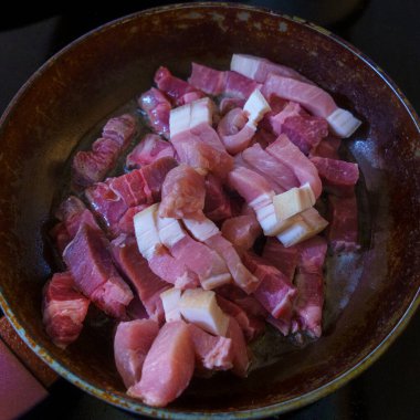 Domuz pastırması kızartma tavasında pişiriliyor. Çiğ kırmızı pastırma.