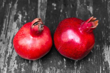 Masada iki kırmızı nar yatıyordu. Masanın üzerinde iki tane olgun kepekli siyah beyaz tahta duvar arkaplanı var. Hayat konsepti.