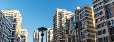 Yüksek binaların yakınındaki sıkışık avlu. Mavi gökyüzünün arka planında büyük bir apartman. Komşuluk kavramları.