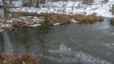 Kış manzarasında küçük bir nehir. Küçük Nehir, ağaçlar ve ilk karlı kış manzarası. Doğa kavramları. Metin için boşluk.