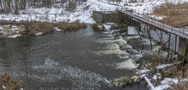Küçük bir nehrin üzerinde eski bir köprü. Kırsal bölgedeki ilk kar. Metin için boşluk.
