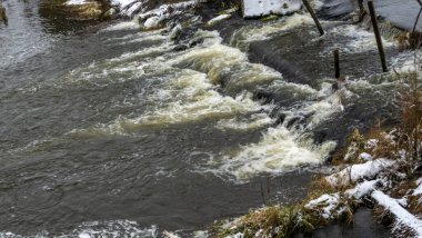 Bir yaya köprüsünün altındaki kış nehrinde kaynar su. Soyut arkaplan. Mesaj için yer var. Doğa kavramları.